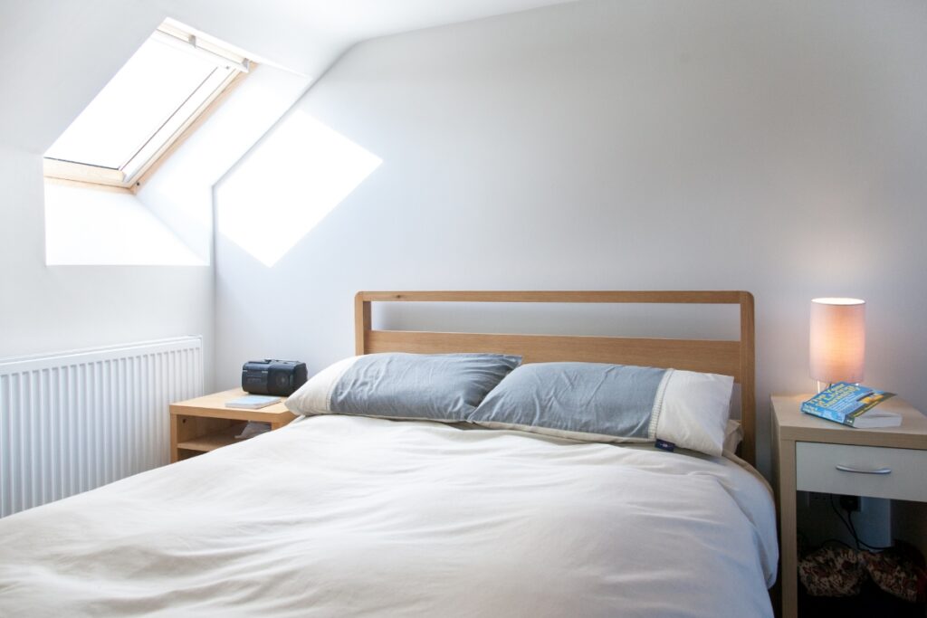 A bright, modern bedroom with a single Velux window illuminating the space.